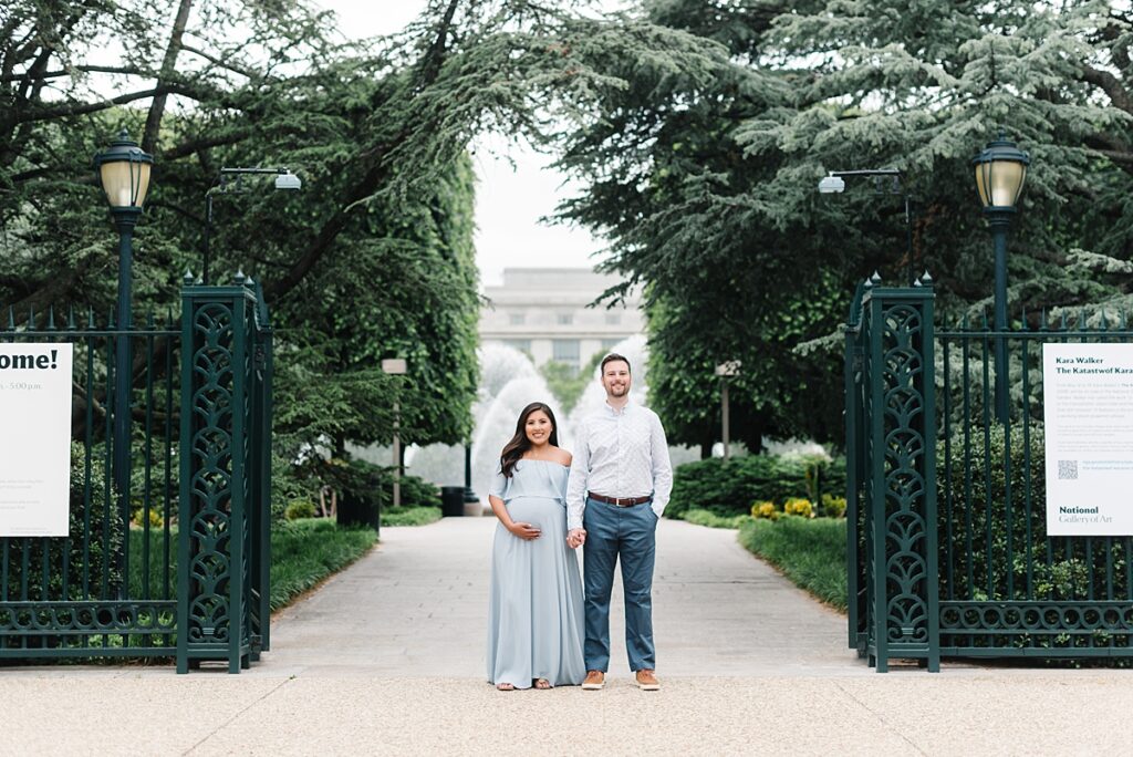 A couple pose for maternity pictures at the garden gates at the National Gallery of Art