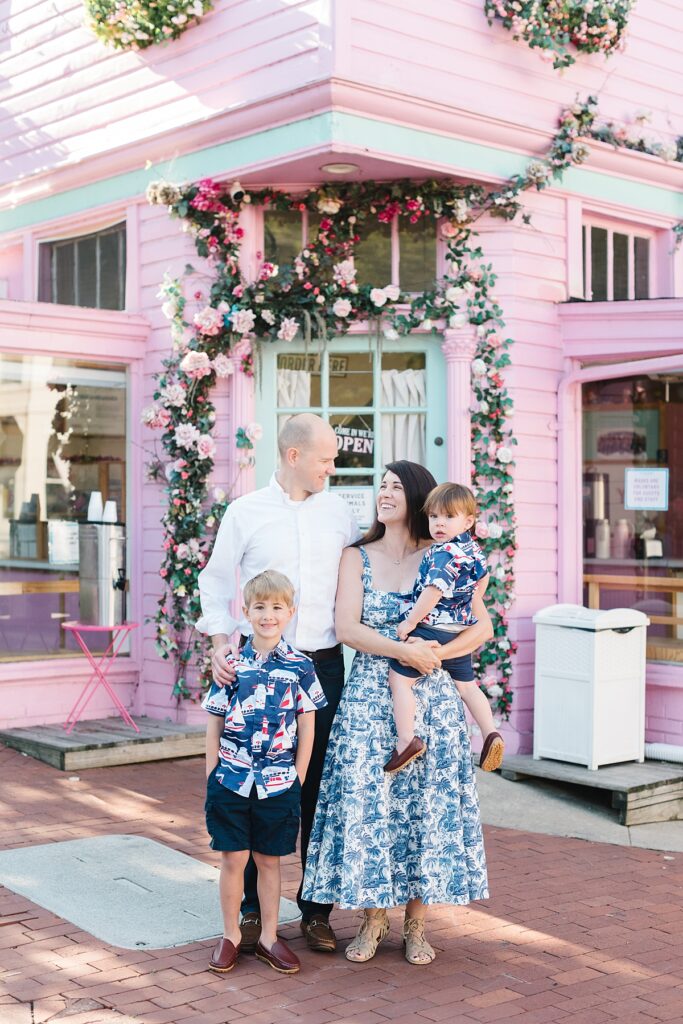 A family poses outside of a pink coffee shop in historic Georgetown during their summer family portrait session with Washington, DC family photographer Mary Catherine Photography