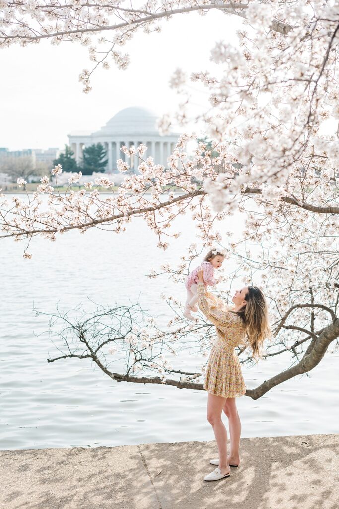 A mother poses for pictures amongst the cherry blossoms at the Tidal Basin by lifting her daughter in the air. 